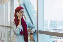 Junge asiatische Geschäftsfrau spricht im modernen Büro auf dem Smartphone — Stockfoto