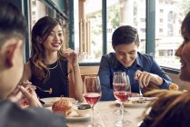 Gesellschaft junger asiatischer Freunde beim gemeinsamen Essen im Café — Stockfoto
