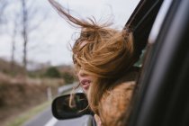 Giovane donna che guarda fuori dal finestrino mentre la macchina viaggia — Foto stock