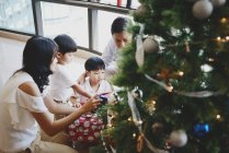 Happy asian family at christmas holidays near fir tree — Stock Photo