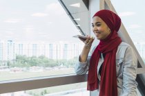 Молода азіатська бізнес-леді розмовляє на смартфоні в сучасному офісі — стокове фото