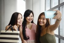 Lindo asiático las mujeres tomando selfie con compras bolsas - foto de stock