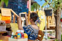 Релаксація Молода жінка фотографує зі своїм мобільним телефоном у кафе — стокове фото