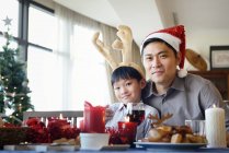 Азиатская семья празднует Рождество, отец и сын за столом — стоковое фото