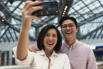 Young casual asian couple taking selfie at shopping mall — Stock Photo