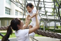 Азіатська мати зв'язується з сином на дитячому майданчику — стокове фото