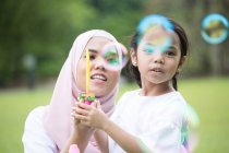 Mother and daughter blowing bubbles. — Stock Photo