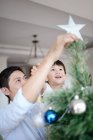 Азіатська сім'я святкує Різдво, батько і син прикрашають ялинку — стокове фото