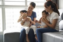 Madres jóvenes vinculándose con sus hijos en la sala de estar - foto de stock