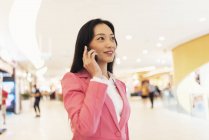 Giovane attraente asiatico donna utilizzando smartphone in shopping mall — Foto stock