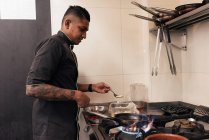 Joven asiático chef cocina en restaurante cocina - foto de stock