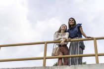 Молодые случайные азиатские девушки, стоящие у забора — стоковое фото