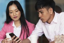 Приваблива молода азіатська пара використовує смартфон разом — стокове фото