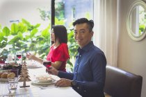 Женщина в элегантном красном платье наслаждается праздничным ужином со своим мужем в их доме в Сингапуре
. — стоковое фото