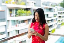 Щаслива азіатська жінка використовує смартфон на балконі — стокове фото