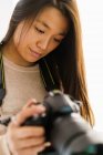 Длинные волосы женщина проверяет на изображения на своей камере — стоковое фото