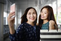 Щасливі красиві азіатські жінки в магазинах беручи selfie — стокове фото