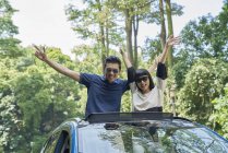 Couple standing through the sun roof of a car — Stock Photo