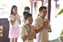 Молодая счастливая азиатская семья молится в святилище — стоковое фото