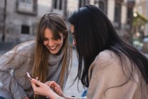 Friends looking at their smartphone on the streets of Madrid — Stock Photo