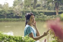 Портрет жінка, слухаючи музику під час прогулянки в ботанічний сад — стокове фото