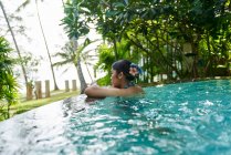 RELEASES Seitenansicht einer jungen asiatischen Frau, die sich in einem Pool entspannt — Stockfoto