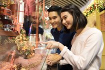 Молода азіатська пара дивиться на речі в торговому центрі — стокове фото