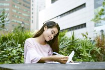 Fröhliche malaiische Frau schreibt fröhlich an Dokumenten im Freien — Stockfoto