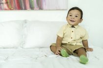 Ein Kind auf dem Bett lächelt, während es auf dem Sofa sitzt — Stockfoto