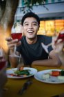 Молодий привабливий азіатський чоловік п'є за столом — стокове фото