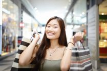Jovem asiático mulher no shopping shopping segurando sacos — Fotografia de Stock
