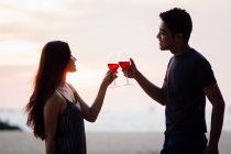 Attractive young asian couple having drink at sunset — Stock Photo