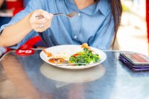 Atractivo asiático mujer comer comida en calle café - foto de stock