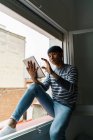 Молодой азиат сидит с табличкой на подоконнике — стоковое фото