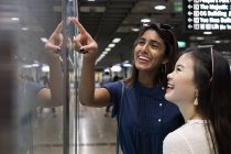 Young casual asian girls looking at map on subway — Stock Photo