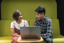 Jeune asiatique couple d'affaires partage ordinateur portable dans le bureau moderne — Photo de stock