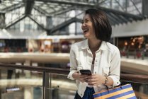 Young casual asian woman using smartphone at shopping mall — Stock Photo