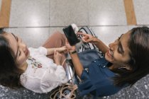 Молодые случайные азиатские девушки делятся смартфоном — стоковое фото