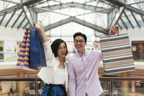Молода випадкова азіатська пара з сумками в магазинах в торговому центрі — стокове фото