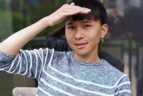 Portrait of asian man covering face from sun and looking at the camera — Stock Photo