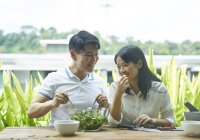 Happy asian couple eating together at home — Stock Photo