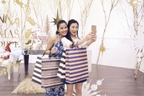 Due giovani asiatica donna shopping insieme nel centro commerciale e prendendo selfie — Foto stock