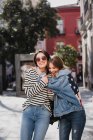 Mujeres jóvenes y guapas chinas y europeas sonriendo en las calles de Madrid - foto de stock