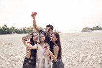 Happy asian friends taking selfie on beach together — Stock Photo