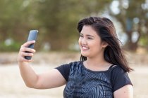 Adolescente con un teléfono de mano tomando selfie. - foto de stock
