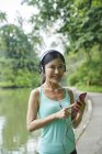Портрет середньому віці жінки прослуховування музики під час прогулянки в ботанічний сад — стокове фото