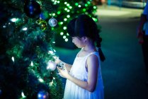 Feliz asiática chica jugando con burbuja cerca de abeto en parque de atracciones en Navidad - foto de stock