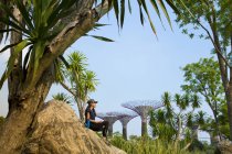 A young singaporean woman is resting at Gardens by the bay from her workout. A water bottle is next to her. — Stock Photo