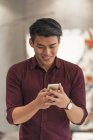 Junger asiatischer Geschäftsmann mit Smartphone im modernen Büro — Stockfoto
