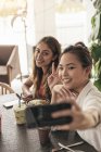 Две молодые красивые азиатские женщины проводят время в кафе — стоковое фото
